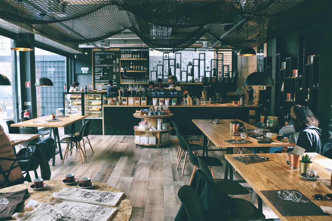 長桌區與開放式吧台的店內全景，空間以水泥與原木為主